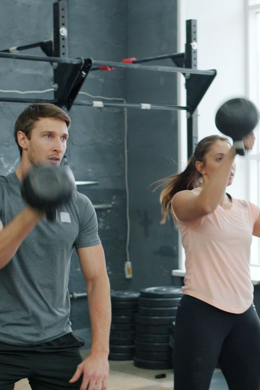A coach and client swinging kettlebells