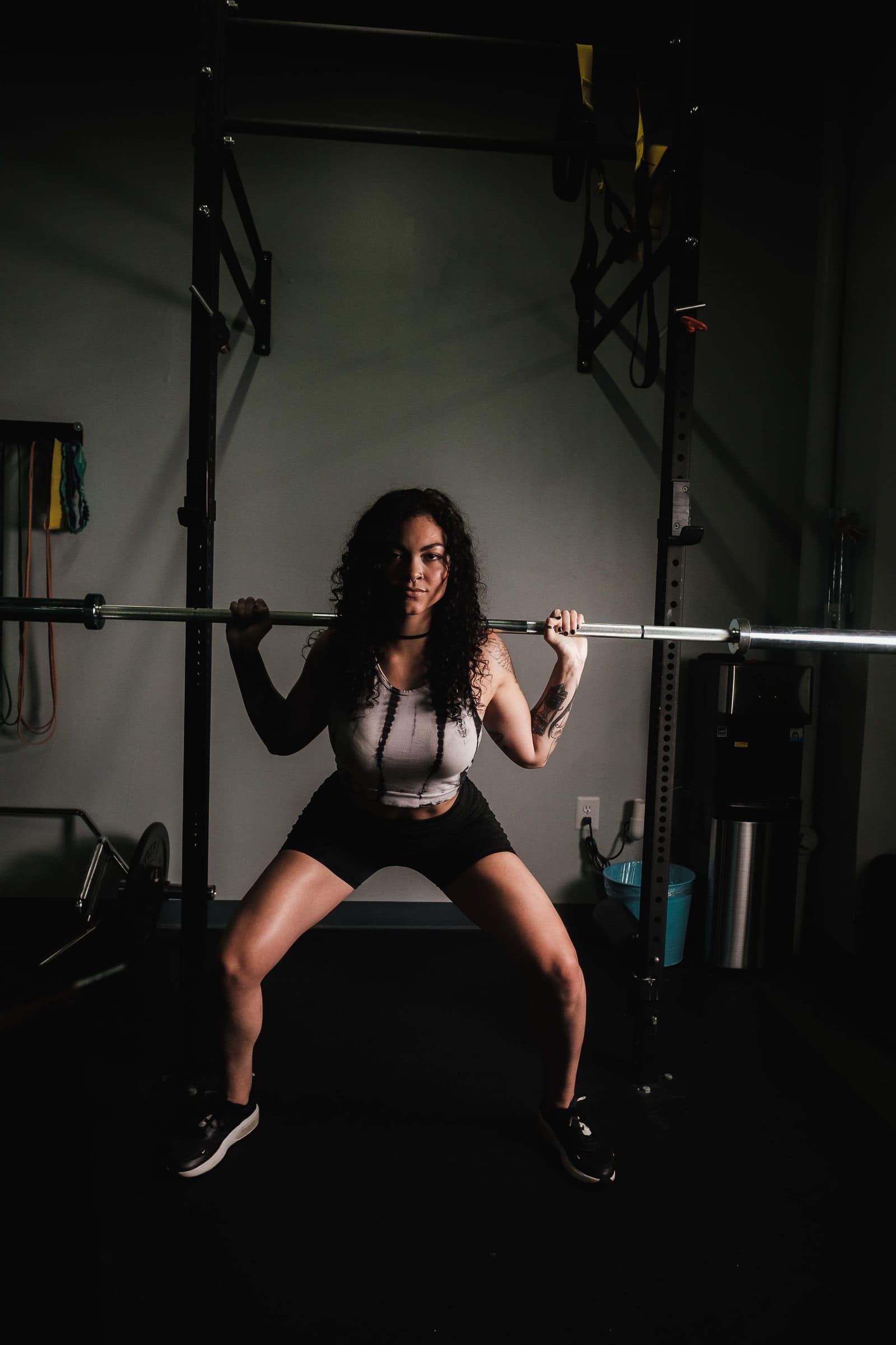 A lifter lowering into a barbell back squat in a small studio