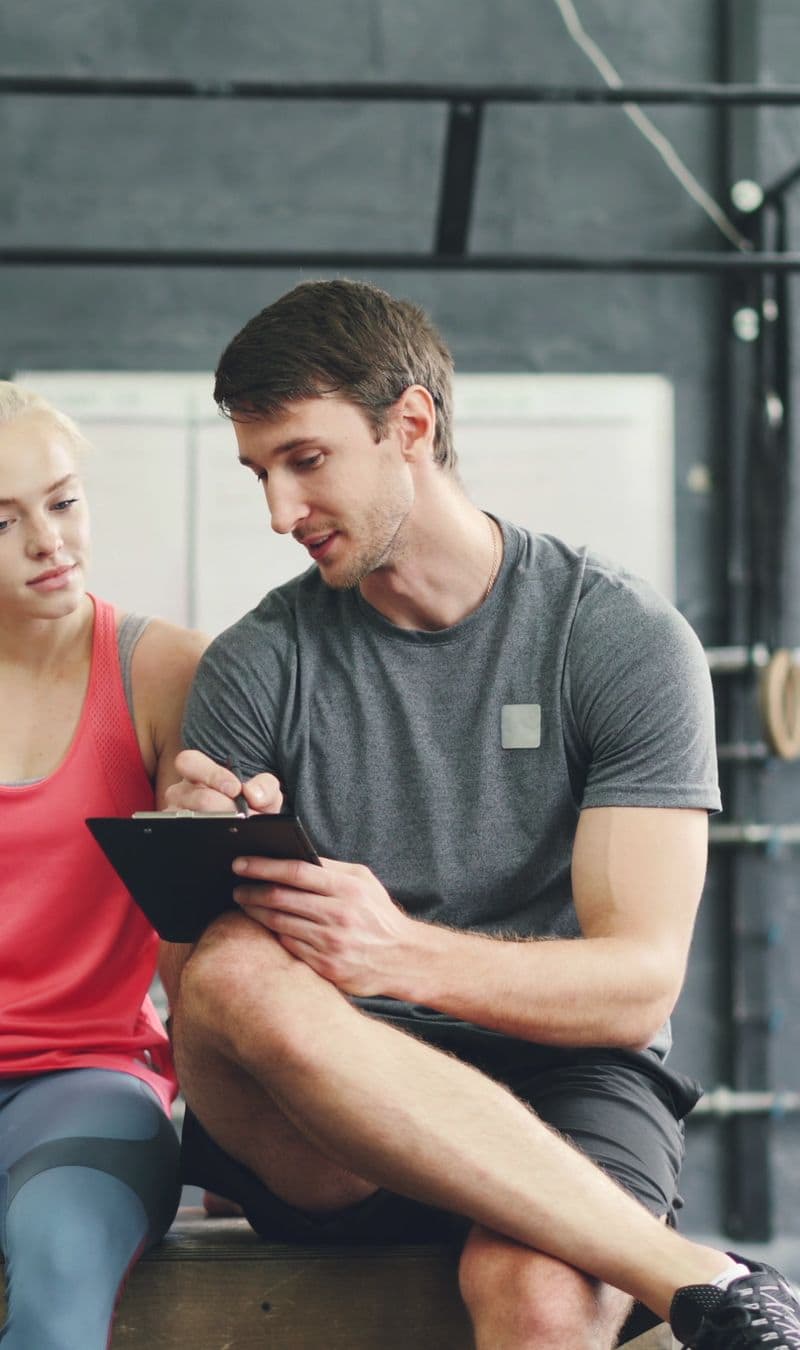 A coach and client reviewing a written training plan on a tablet