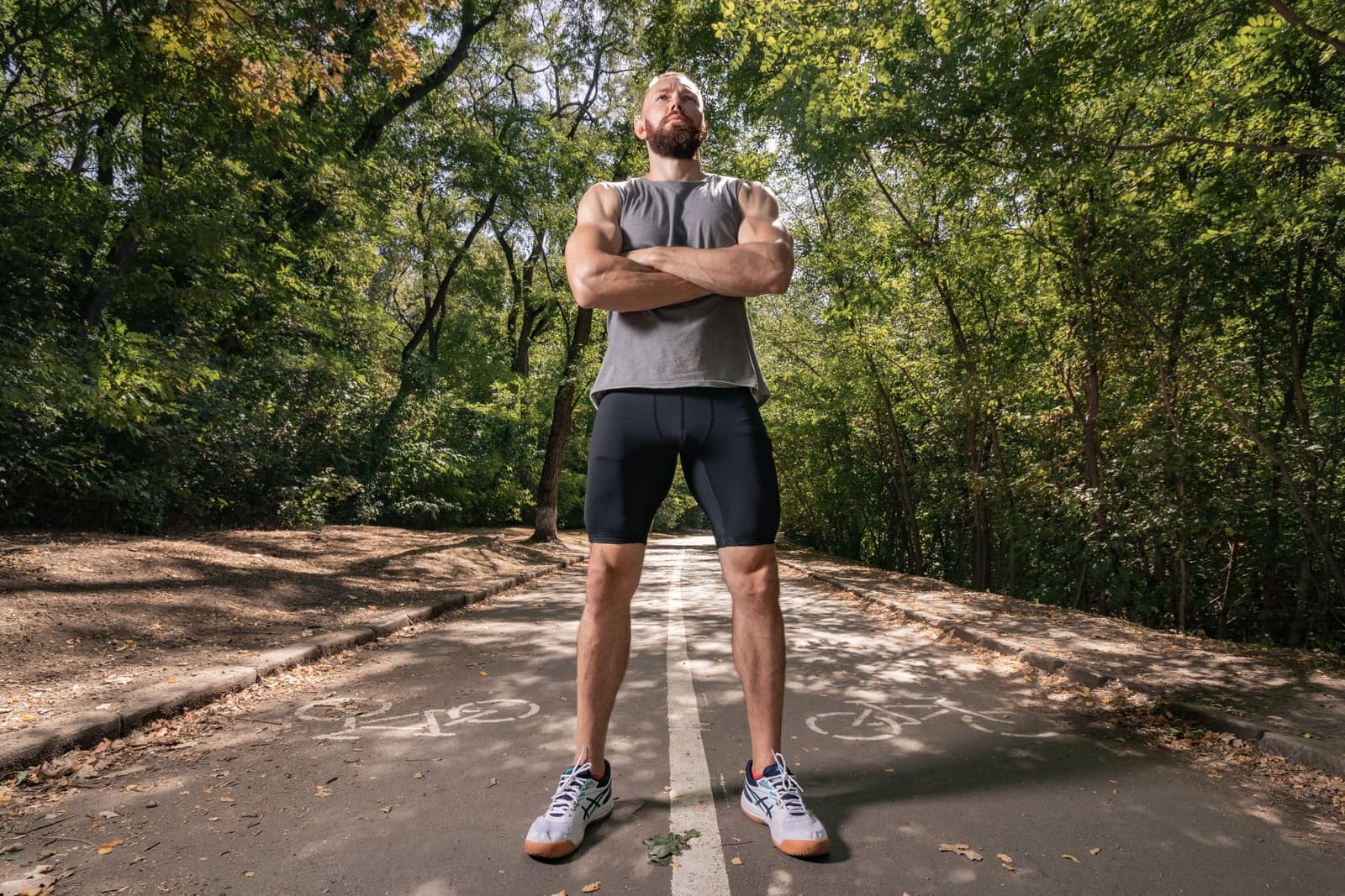 A man training on a tree-lined park path in the morning