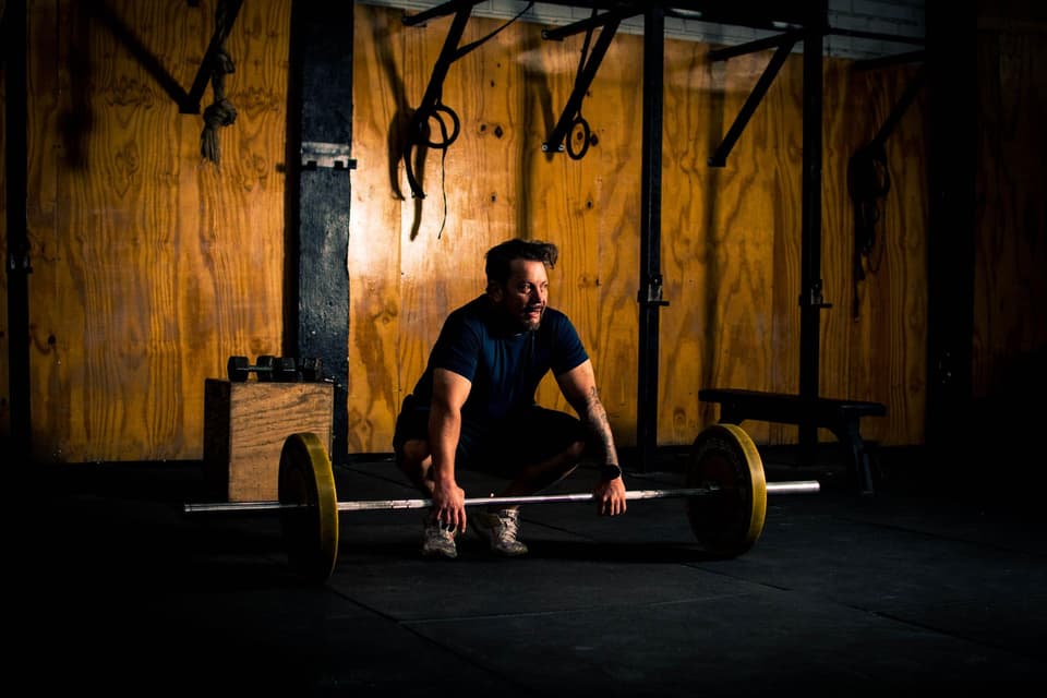 A lifter setting up a deadlift in a timber-walled gym